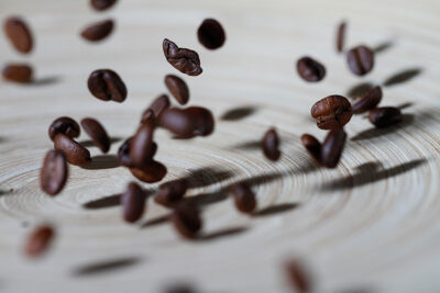Nahaufnahme von Kaffeebohn die auf einen Teller fallen, als Freeze-Motion-Aufnahme fotografiert
